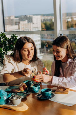 Smiling female friends drinks coffee and eating dessert in restaurant during lunch time