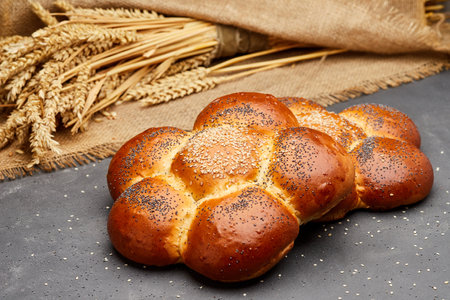 Freshly baked braided challah bread topped with sesame and poppy seeds, perfect for any meal