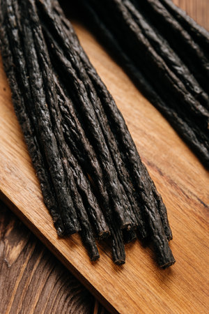 Smoked meat sticks with herbs and spices on a rustic board, ideal for gourmet food presentationsの写真素材