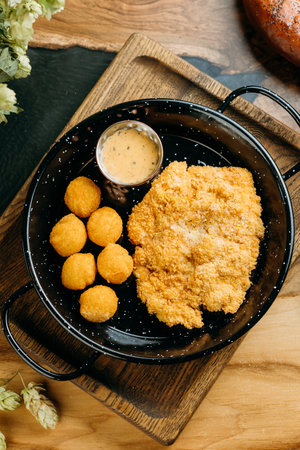 Crispy breaded chicken fillet with golden potato croquettes and creamy dipping sauceの写真素材