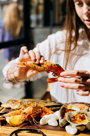 Young woman peeling shrimp at seafood restaurant, perfect for food lifestyle and dining out contentの写真素材