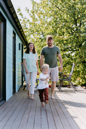 A joyful family walking together on a sunny day, with their child leading the way in playful momentの写真素材