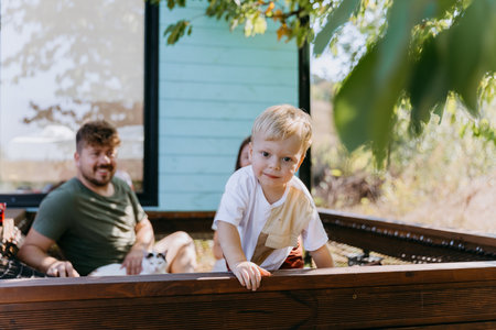 Curious toddler playing outside with family in relaxed and cozy atmosphere, enjoying nature togetherの写真素材