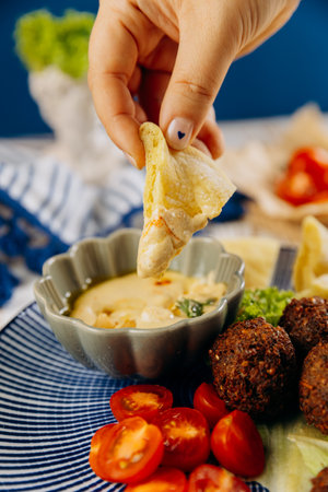 Hand dipping pita bread in creamy hummus. Perfect Middle Eastern snack experienceの写真素材