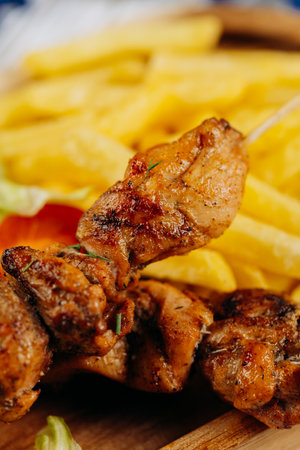 Close-up of juicy grilled chicken skewers served with crispy fries, perfect for lunch or dinnerの写真素材