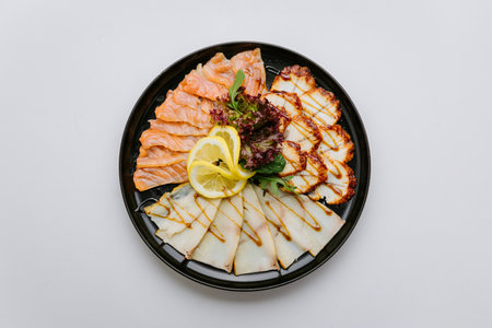 Gourmet seafood platter with salmon, white fish, and chicken slices garnished with lemon and greensの写真素材