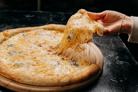 Melting cheesy pizza slice being lifted, showcasing gooey cheese pull, perfect for pizza lovers