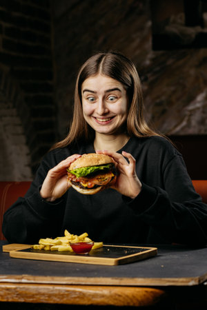 Playful woman enjoying a classic burger with fries and ketchup, perfect comfort food moment