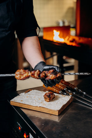 Chef holding skewered grilled meat ready to serve, highlighting BBQ experience with rich flavorsの写真素材