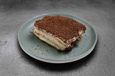 Classic tiramisu dessert with cocoa topping served on a green plate, perfect for any sweet lover