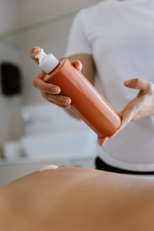Applying soothing body lotion for a relaxing massage experience in a calming spa environmentの写真素材