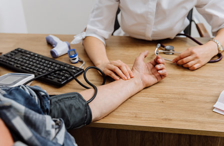 Healthcare professional checking patients pulse and blood pressure in medical consultation settingの写真素材