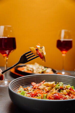 Savoring a colorful vegetable salad with red wine for a perfect gourmet dining experienceの写真素材