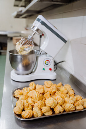 Freshly baked profiteroles beside a professional mixer in a commercial kitchen setting