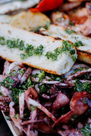 Grilled bread and calamari topped with fresh herbs for a gourmet seafood dining experienceの写真素材