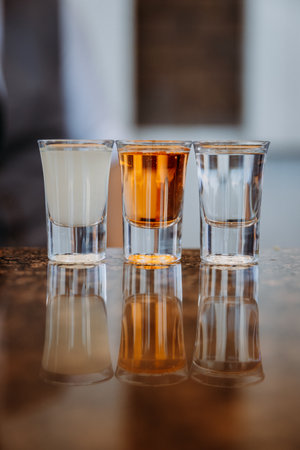 Three glasses of diverse drinks reflecting on a shiny surface for a modern beverage concept