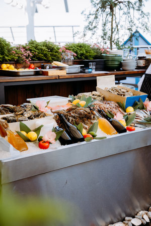 Seafood buffet with fresh oysters, prawns, and drinks displayed for dining in vibrant settingの写真素材