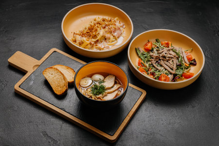 A flavorful trio of pasta, salad, and soup with bread, perfect for a balanced and satisfying mealの写真素材