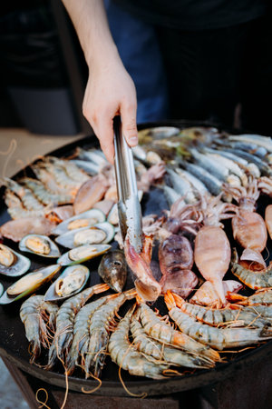 Chef grilling fresh seafood on a hot plate, showcasing shrimp, mussels, and squid for gourmet diningの写真素材