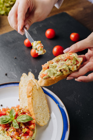 Fresh guacamole bruschetta topped with colorful vegetables, served on a crispy baguette sliceの写真素材