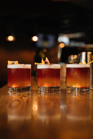 Three vibrant cocktails on a wooden bar counter, perfect for nightlife and mixology themes