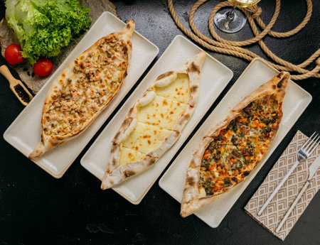 Assorted Turkish pide with cheese, minced meat and chicken served on plates in a gourmet setting