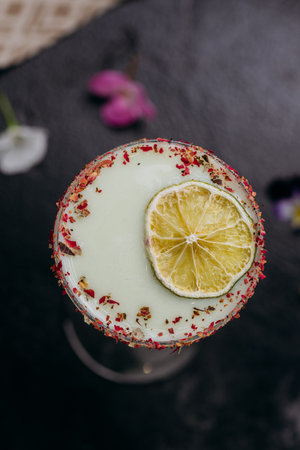 Elegant citrus cocktail in tall glass with floral garnish and dried lime slice, perfect for summerの写真素材