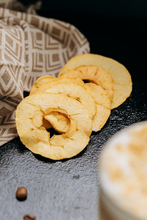 Crispy dried apple rings on dark textured background, perfect for healthy snacking and food styling