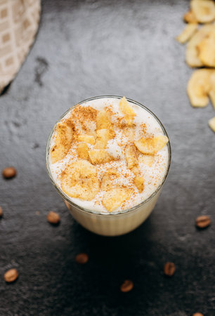 Creamy latte with whipped foam and cinnamon, served on a dark textured surfaceの写真素材