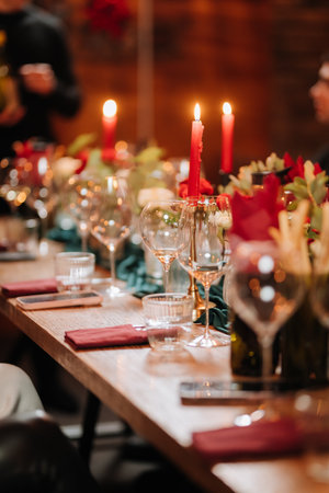 Elegant candlelit dinner table setup with wine glasses and red accents in cozy atmosphereの写真素材