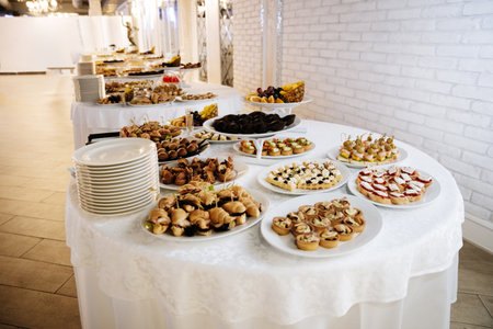 Elegant buffet table with gourmet canapes, desserts and fruit at festive banquet event