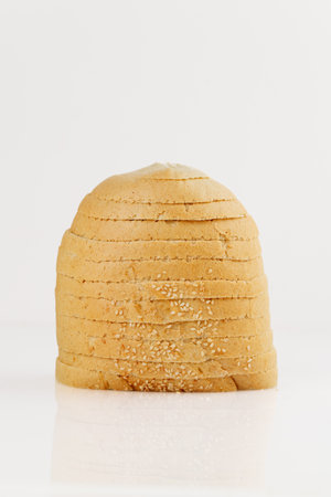 Sliced round sesame bread loaf isolated on white background, close-up studio shot