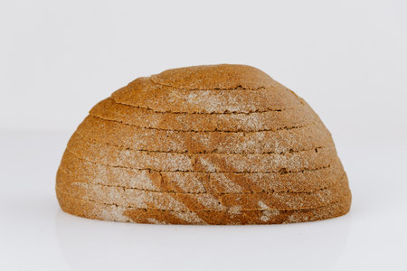 Sliced whole grain bread loaf on white background, rustic and healthy bakery product