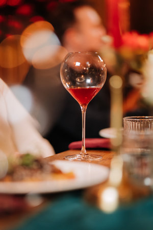 Elegant glass of red wine on festive dinner table with romantic candlelight ambianceの写真素材