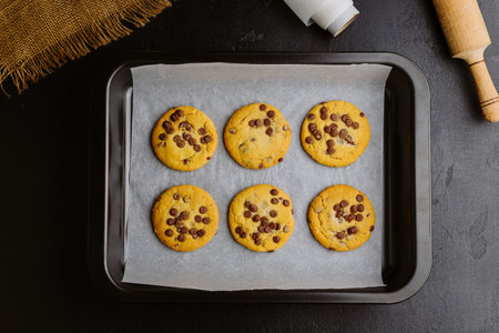 Golden brown chocolate chip cookies cooling on tray, perfect homemade sweet snack