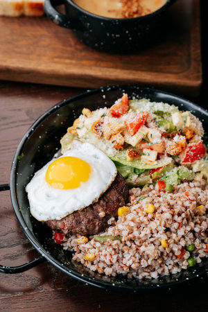 Healthy lunch bowl with buckwheat, beef patty, sunny-side egg and fresh Caesar saladの写真素材