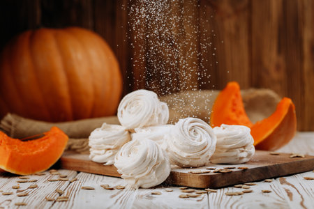 Pumpkin marshmallow sweets with powdered sugar falling, rustic autumn wooden backgroundの写真素材