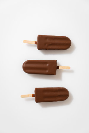 Chocolate ice cream popsicles on white background. Minimalist summer dessert conceptの写真素材