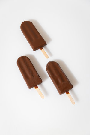Chocolate ice cream popsicles on white background. Minimalist summer dessert conceptの写真素材