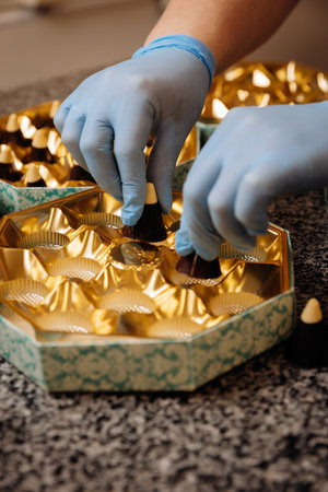 Placing premium handmade chocolates into elegant golden packaging, close up view