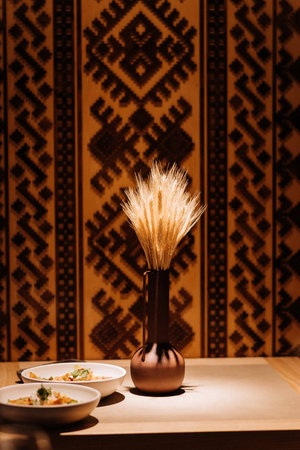 Traditional wheat bouquet in a clay vase with ethnic background and warm cozy lightingの写真素材