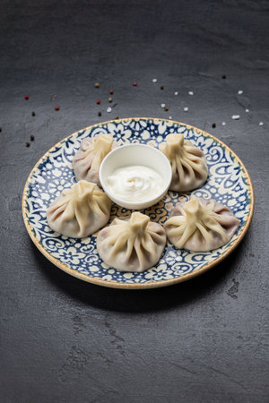 Traditional Georgian khinkali dumplings with sour cream sauce on ceramic plateの写真素材