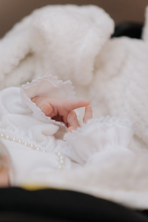 Newborn baby hand in white baptism outfit with lace and pearls symbolizing purity and loveの写真素材