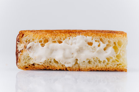 Close-up of airy croissant slice filled with creamy vanilla tiramisu cream on white backgroundの写真素材