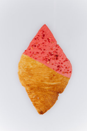Golden croissant with pink strawberry glaze on white backgroundの写真素材