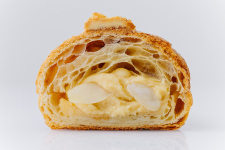Almond croissant cut in half with creamy filling and powdered sugar on white backgroundの写真素材