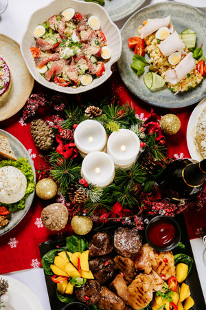 Festive dinner table with assorted holiday dishes, candles, and Christmas decorationsの写真素材