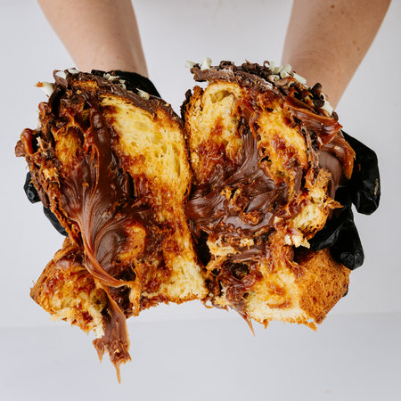 Hands in gloves breaking chocolate filled Christmas panettone, rich festive dessertの写真素材