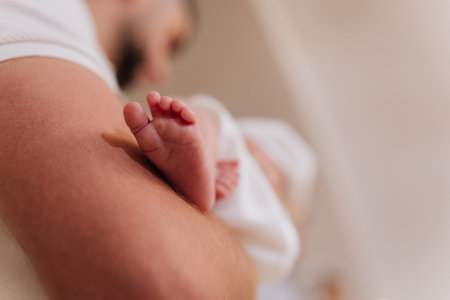 Closeup newborn baby foot resting on fathers arm tender family momentの写真素材
