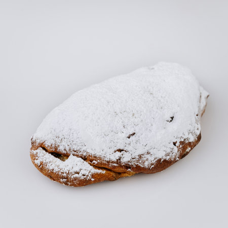 Traditional Christmas stollen loaf with powdered sugar on white background, holiday dessertの写真素材